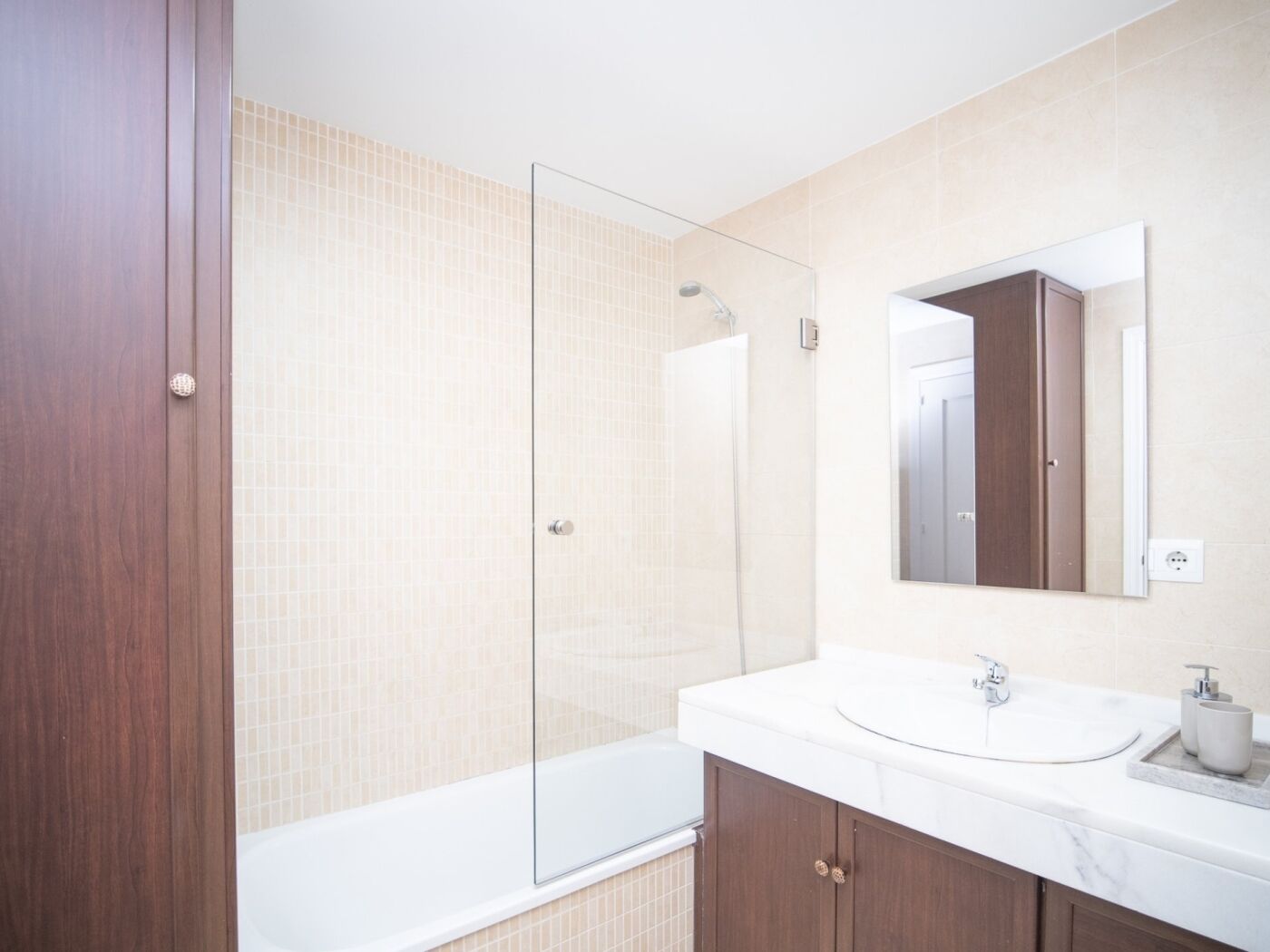 A modern bathroom with a glass shower enclosure, a white sink, and a large mirror.