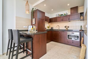 A kitchen with a central island, bar stools, a built-in oven, and a hanging light fixture. - Apartment 'Casa Limón' with Sea View, Wi-Fi and Air Conditioning (Nerja)