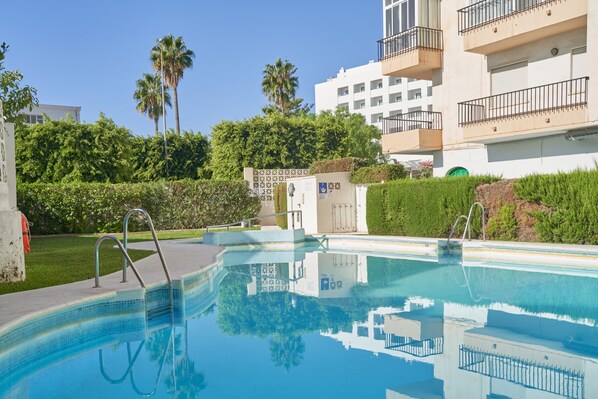 A swimming pool with clear water, surrounded by greenery and a building with balconies. - Holiday Apartment "Albaida 3j" near Beach with Shared Pool & Wi-Fi (Nerja)