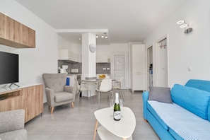 Un salon moderne avec un téléviseur, un canapé et un coin repas.