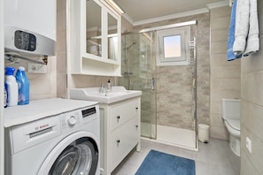 A modern bathroom with a Bosch washing machine, a glass shower enclosure, and a white sink. - Holiday Apartment "Albaida 3j" near Beach with Shared Pool & Wi-Fi (Nerja)