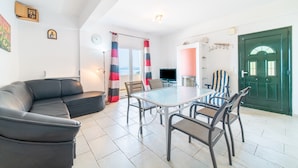 A living room with a black sofa, a glass-top dining table, and striped curtains. - Apartment 'Alex' with Wi-Fi and Air Conditioning (Corfu)