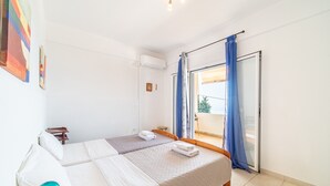 A bedroom with a bed, a desk, a chair, and a window with curtains. - Apartment 'Alex' with Wi-Fi and Air Conditioning (Corfu)