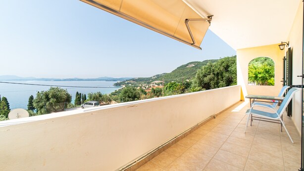 A balcony with a view of the sea, a table, and two chairs. - Apartment 'Alex' with Wi-Fi and Air Conditioning (Corfu)