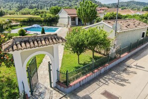 A residential property with a swimming pool, a paved pathway, and a fenced garden area.