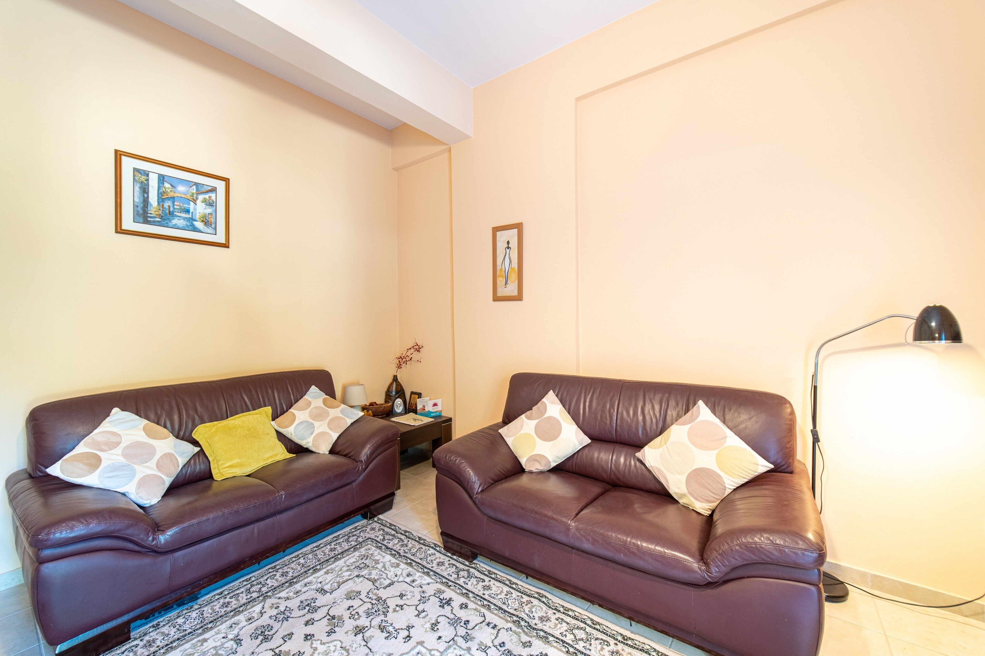 A living room with two brown leather sofas, a patterned rug, and a lamp.