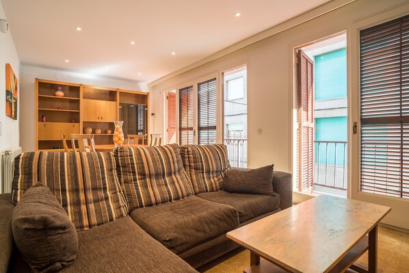 A living room with a sectional sofa, a wooden coffee table, and a dining area with a wooden table and chairs.