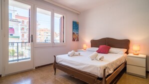 A bedroom with a bed, two bedside lamps, a nightstand, a window, and a painting on the wall.