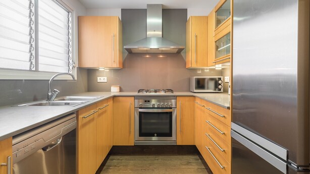 A compact kitchen with a dishwasher, oven, microwave, and stainless steel refrigerator.