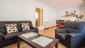 A living room with a sofa, armchair, coffee table, and a painting on the wall.