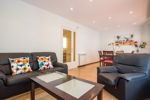 Un salon comprenant un canapé, un fauteuil, une table basse et un tableau accroché au mur.