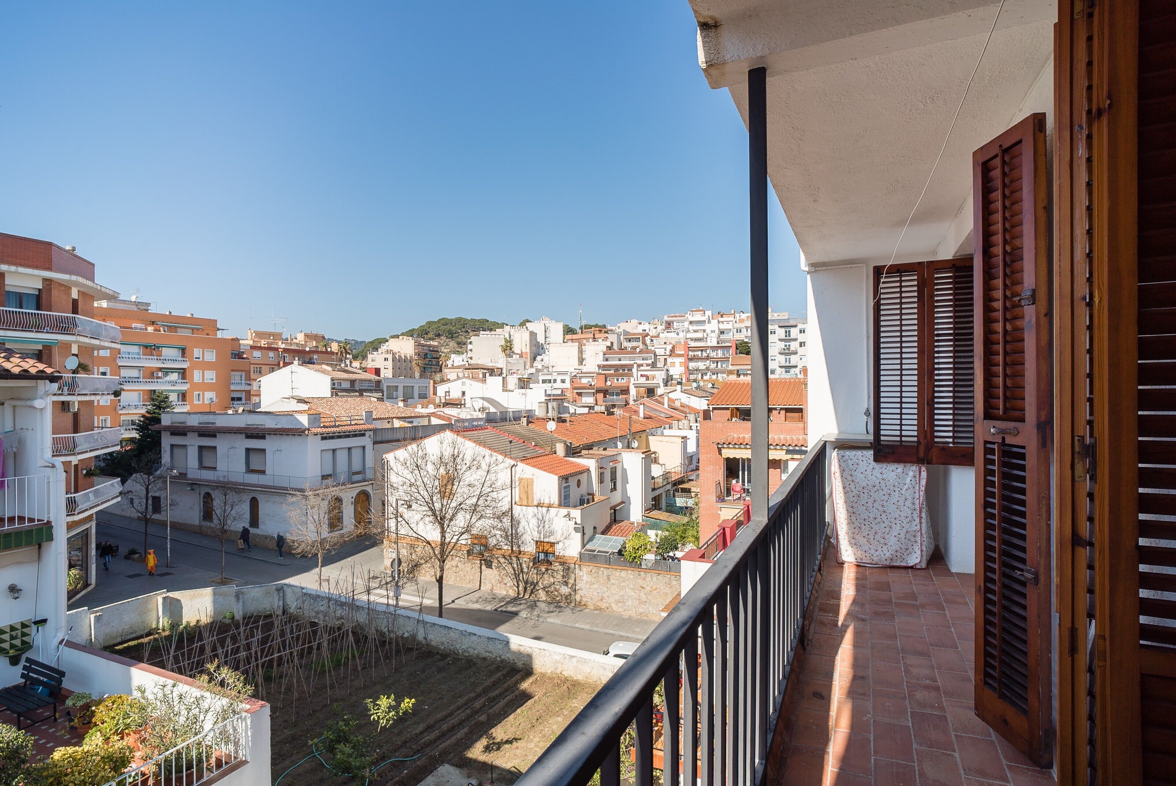 Ein Balkon mit Blick auf ein Wohngebiet, mit Gebäuden, blauem Himmel und Fliesenboden.