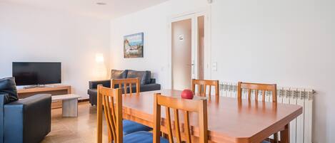 A modern living room with a TV, sofa, and dining table with chairs.