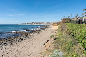 Una playa con costa rocosa, una playa de arena y un edificio con techo plano.