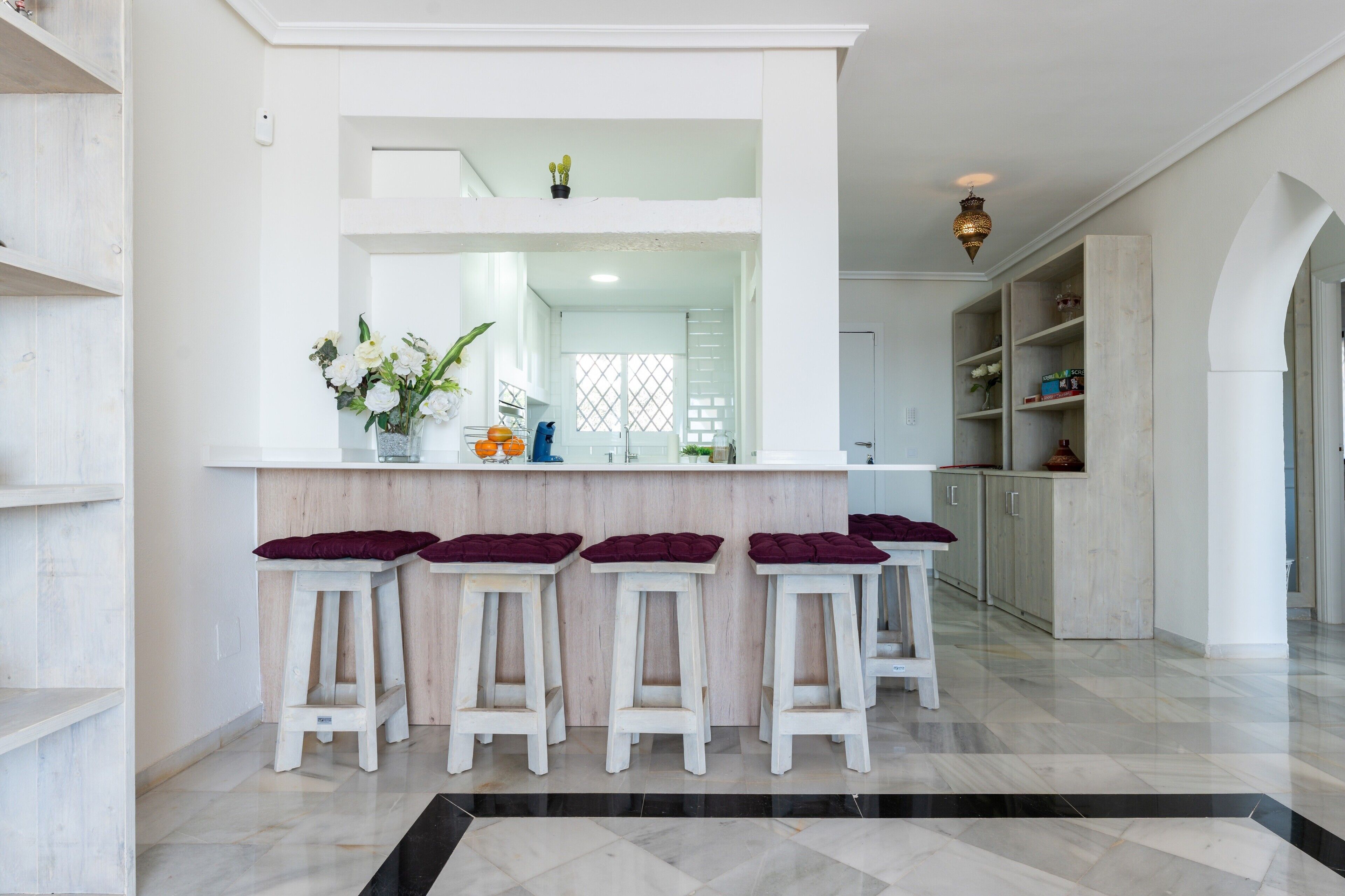 A kitchen with a central island, bar stools, and a view into the dining area.