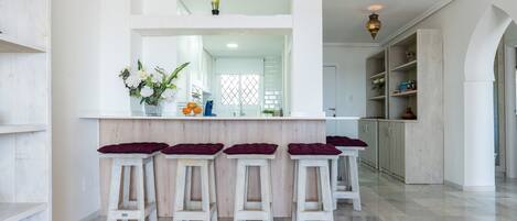 A kitchen with a central island, bar stools, and a view into the dining area.