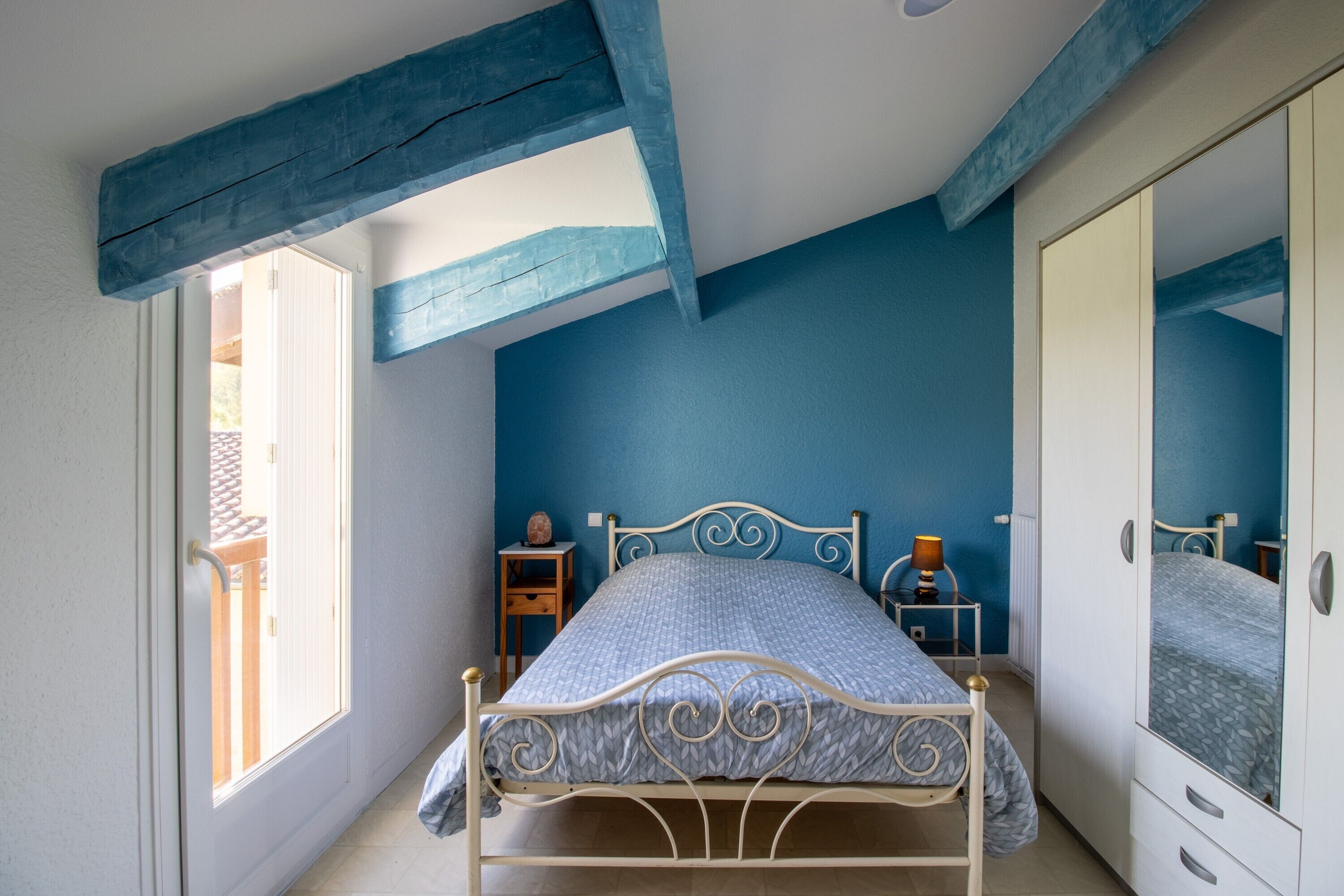 Ein Schlafzimmer mit Bett, Nachttischen, einem Kleiderschrank und einem Fenster.