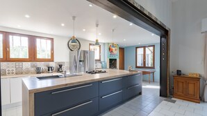 A modern kitchen with a large island, built-in appliances, and pendant lighting.