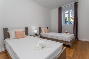 Una habitación de hotel con dos camas, una mesita de noche con lámpara y un ventanal con cortinas.