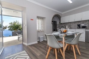 Cocina moderna con comedor, vista al mar y un pequeño cubo de basura.