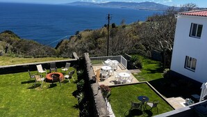 Ein Küsteneigentum mit einer Terrassenfläche, Gartenmöbeln und Blick auf das Meer und die Berge.