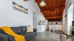 Ein Wohnzimmer mit einer Couch, einem Esstisch und einer Küche im Hintergrund.