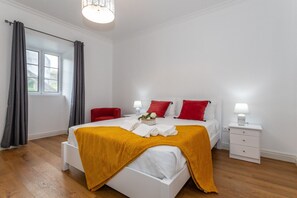 Een hotelkamer met een bed, twee nachtkastjes, een stoel, een raam met gordijnen en een lamp.