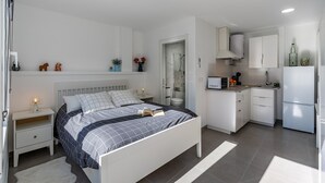 Un dormitorio moderno con cama, mesitas de noche y un pequeño escritorio.