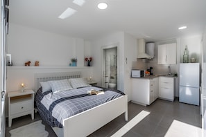 Un dormitorio moderno con cama, mesitas de noche y un pequeño escritorio.