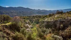 Paisaje montañoso con cielo despejado, un valle con vegetación y un pueblo distante.