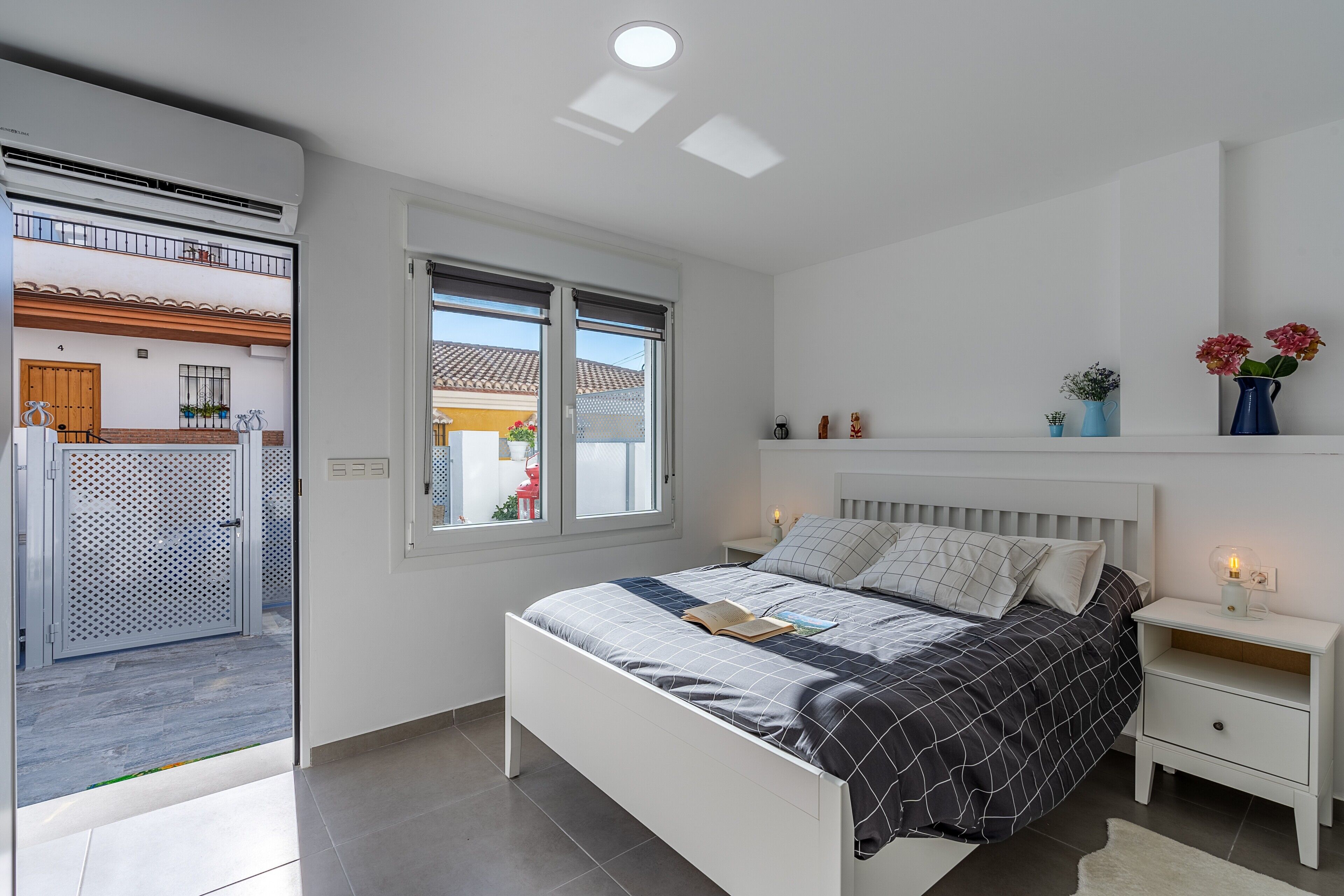 Ein Schlafzimmer mit Bett, Nachttischen, einem Fenster und Blick ins Freie.