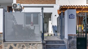 Una entrada protegida por un portón de metal, escalones de piedra y un letrero que dice 'Alicia la Pura'.