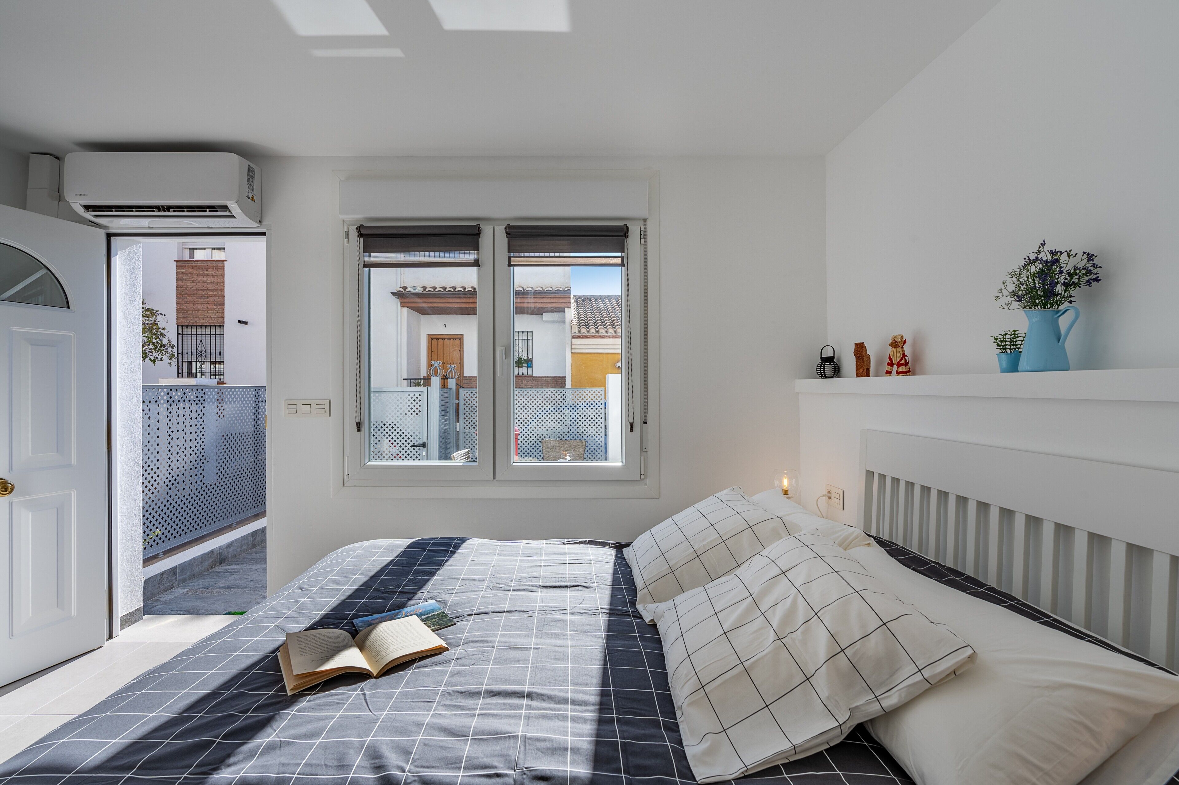 Ein Schlafzimmer mit Bett, einem offenen Balkon, einem Fenster und einer Heizung.