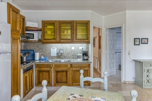A kitchen with wooden cabinets, a microwave, a stove, and a dining table with chairs.