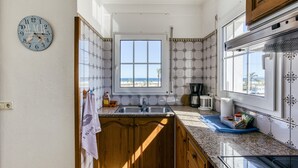 Una cocina con ventana, armarios de madera, un lavamanos y un reloj.