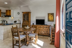 Une cuisine avec des meubles de rangement en bois, une table de salle à manger ronde et un téléviseur.