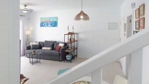 Un salon moderne comprenant un canapé, une table basse, une bibliothèque et un ventilateur de plafond.