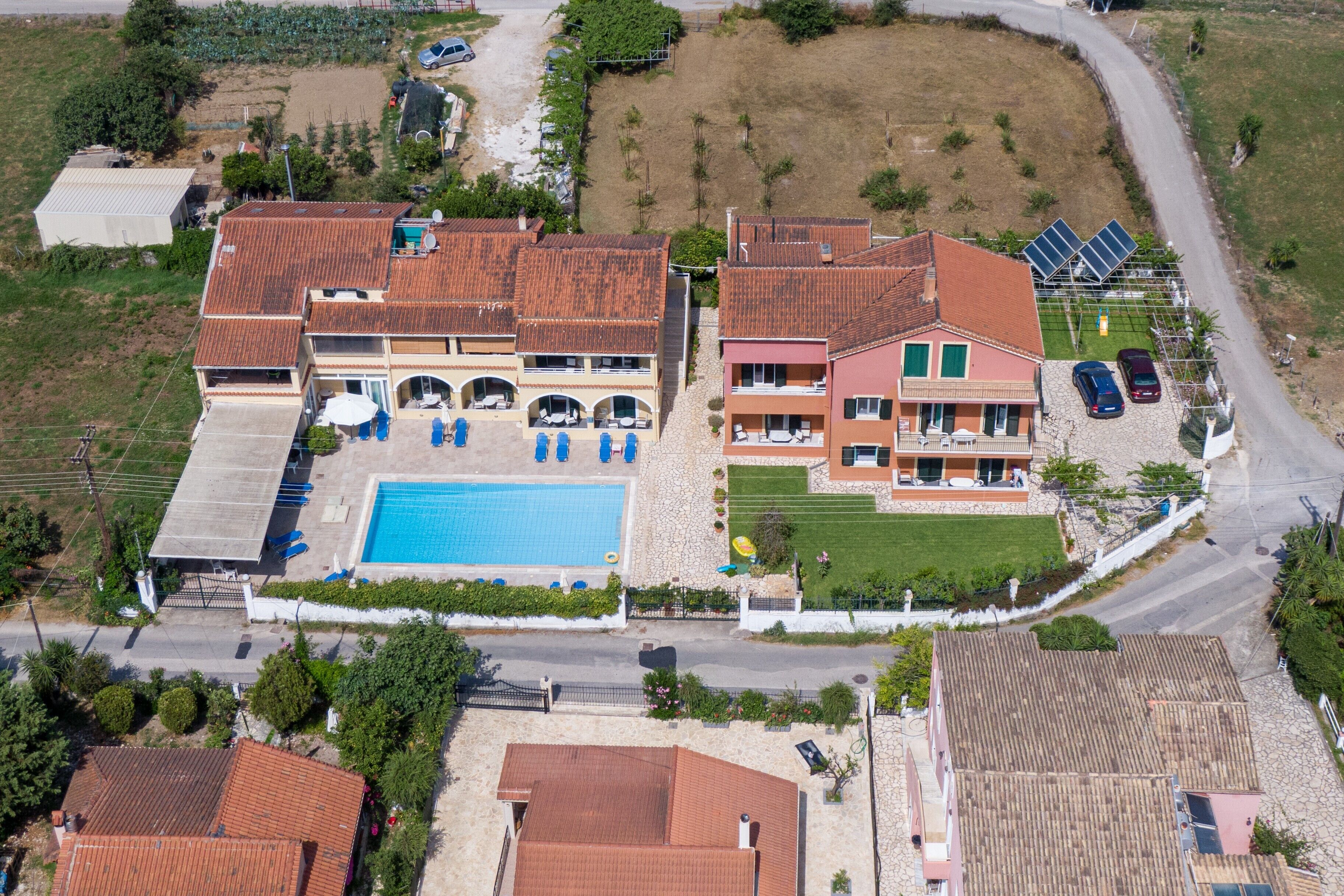 A large house with a swimming pool, multiple balconies, and a small garden.
