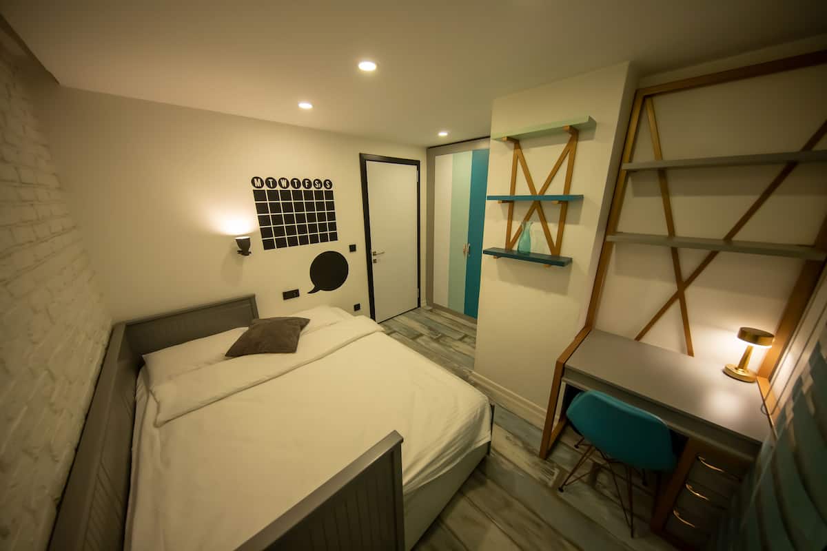 Un dormitorio con una cama, un escritorio con silla y un armario.