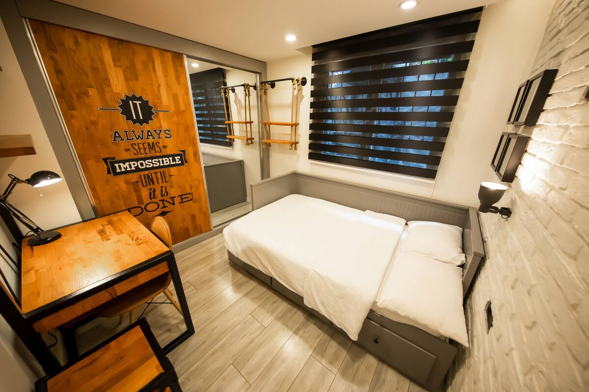 Un dormitorio moderno con un escritorio de madera, una cama y una cita motivacional en la pared.
