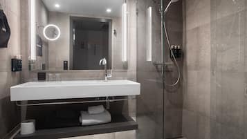 A modern bathroom with a large sink, mirror, and glass-enclosed shower.