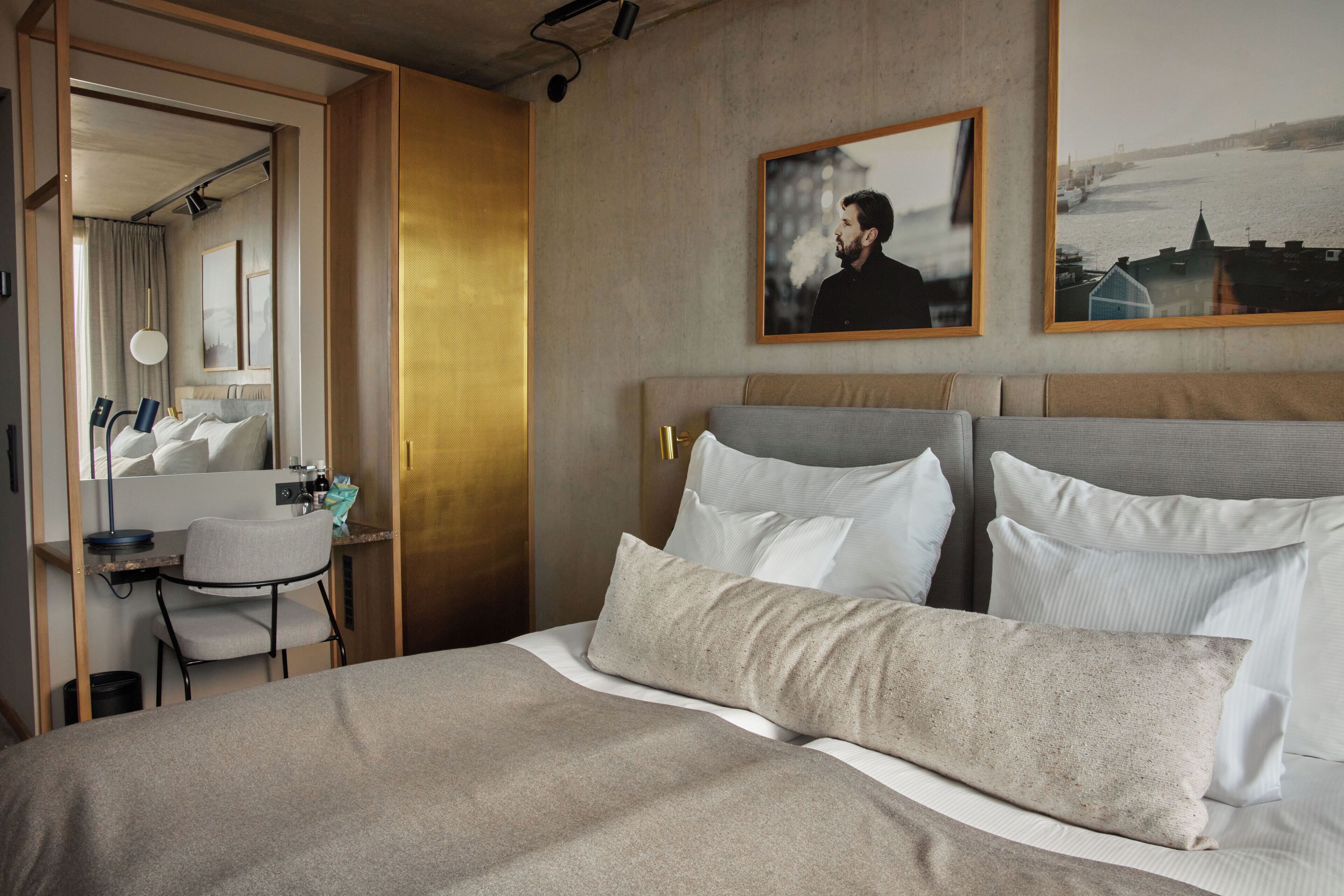A hotel room with a bed, a desk, a chair, and a large window.