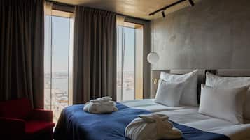 A hotel room with a large bed, a red chair, and two towels on the bed.