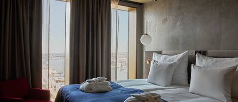 Habitación de hotel con una cama grande, una silla roja y dos toallas sobre la cama.
