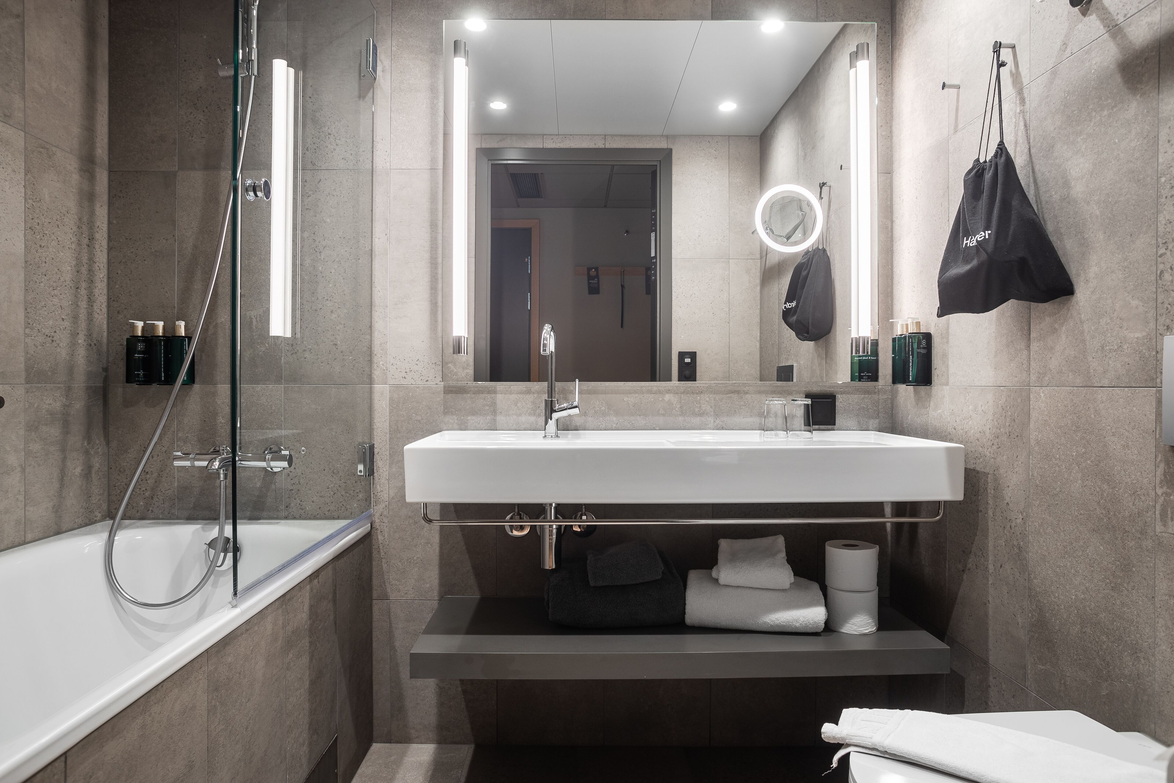 Une salle de bain moderne avec un lavabo blanc, une douche à parois de verre et un grand miroir.