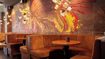A restaurant with booth seating and a colorful abstract mural on the wall.