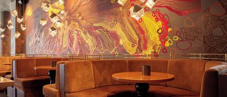 Un restaurant avec des banquettes et une fresque murale abstraite et colorée.
