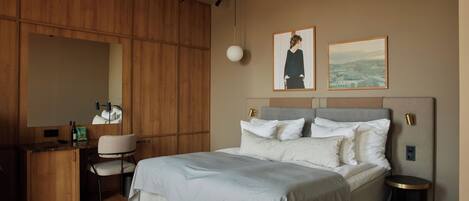 Un dormitorio moderno con una cama grande, un escritorio y una silla. Hay dos cuadros en la pared.