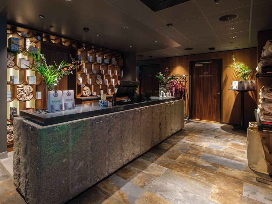 A reception area with a stone counter, wooden paneling, and a display of toiletries.