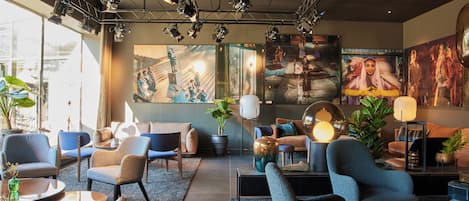 Un moderno vestíbulo de hotel con zonas de estar, ventanas amplias y obras de arte en las paredes.